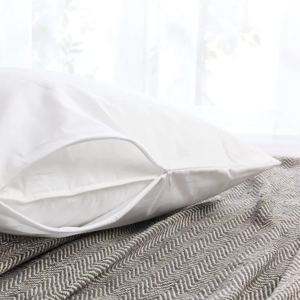 A white Hotel Pure Luxury polycotton pillow protector. You can see the zipper that's currently slightly open so you can see the pillow inside. The pillow is sitting on a grey blanket.