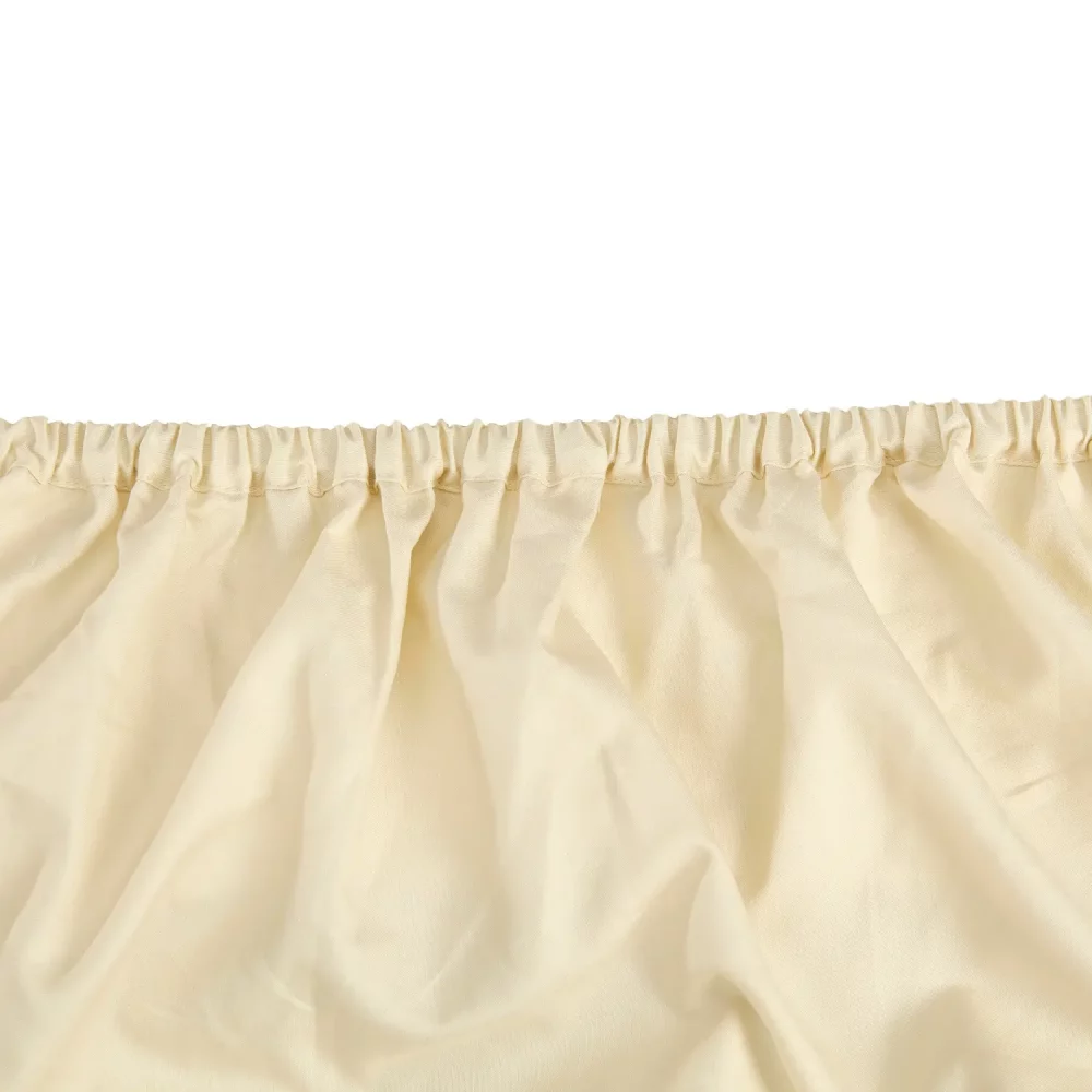 A close-up view of a Hotel Pure Luxury branded cream coloured cotton fitted sheet.
