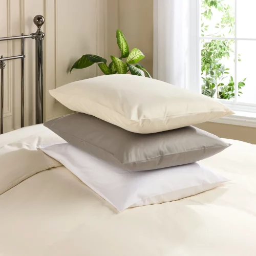 Three Hotel Pure Luxury 480 thread count classic pillowcases encasing pillows stacked on top of each other. In cream, grey and white.