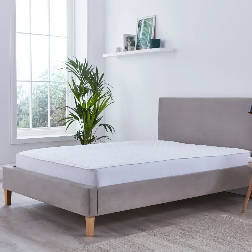 A Martex 100% cotton quilted mattress protector sitting on a mattress.
