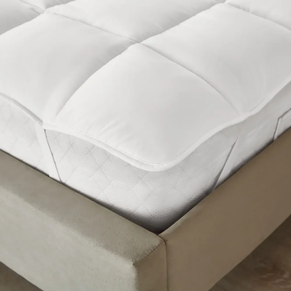 A close up of a 100% microfibre Martex cosy touch mattress topper on top of a bed.