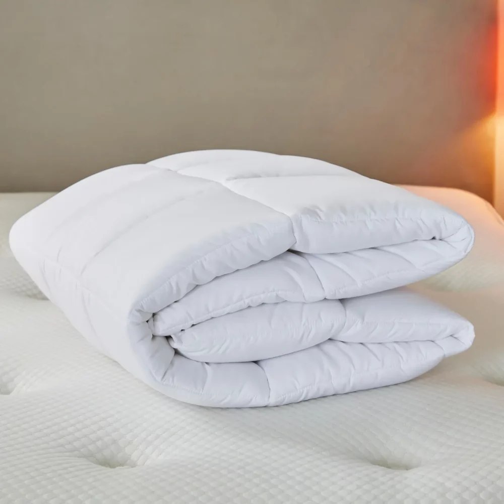A Martex cosy touch mattress topper folded up and sitting on a bed.