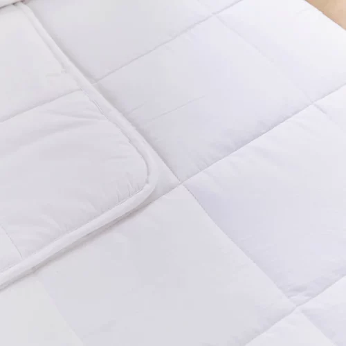 A close up look at a white temperature regulating 4 tog cot bed duvet from Martex Baby. The duvet has a square grid design.