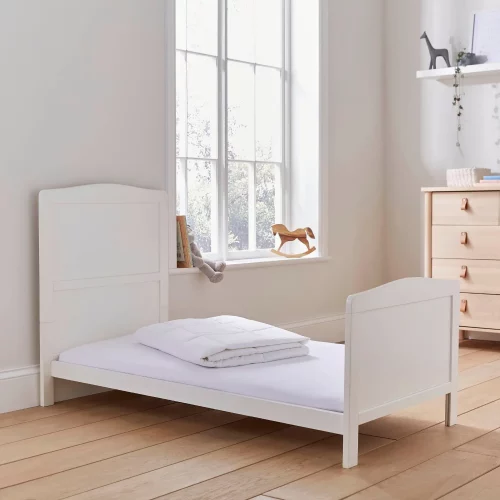 A Martex Baby temperature regulating 4 tog cot bed duvet folded up on a bed in a child's bedroom.