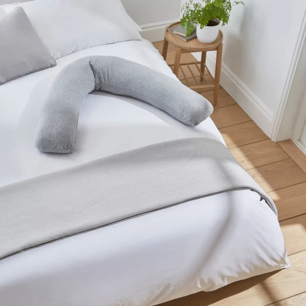Martex Baby pregnancy and nursing pillow in grey and sitting on a bed.