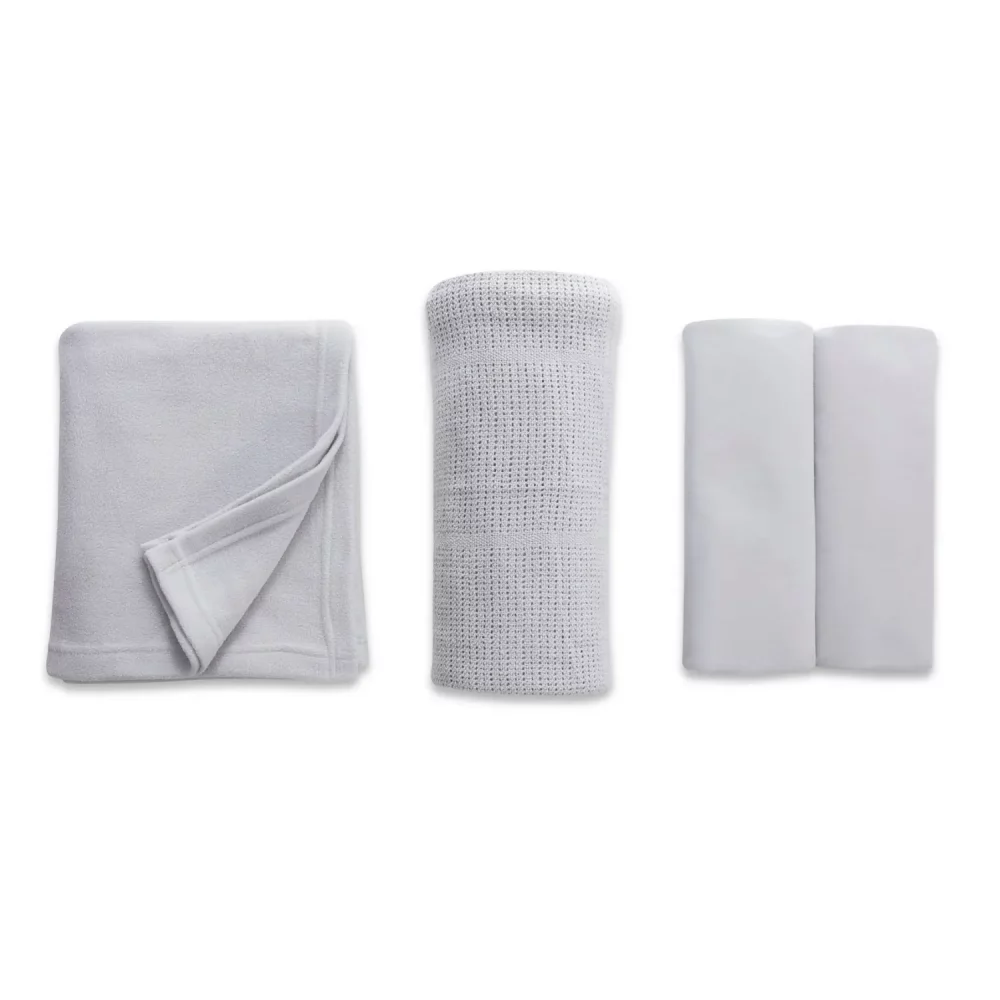 A grey cot bed starter set from Clair De Lune. It contains a fitted sheet, cellular blanket, and polar fleece blanket.