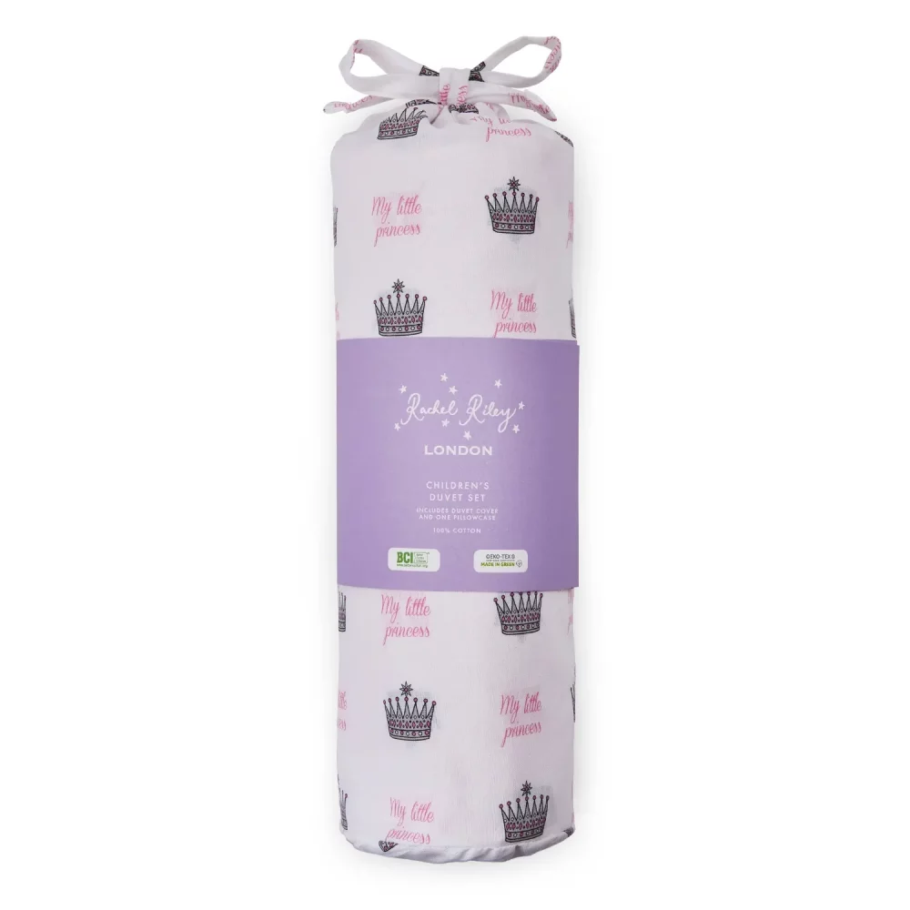 A white duvet cover and pillowcase set from Rachel Riley in its packaging. It comes in a bag which features a print of small crowns all across it with pink writing that says 'My Little Princess'.