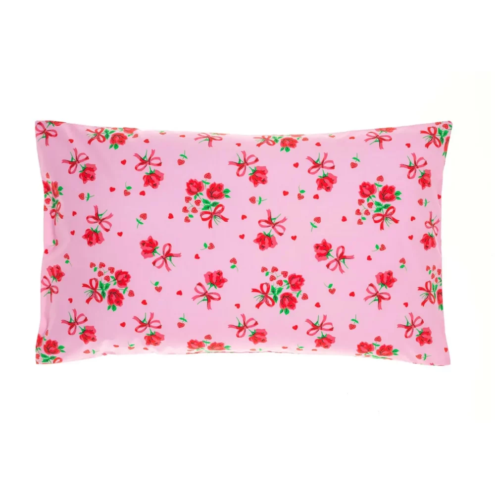A pink strawberry rose pillowcase from Rachel Riley. The pattern includes roses with a red bow tied underneath them, and small red love hearts.
