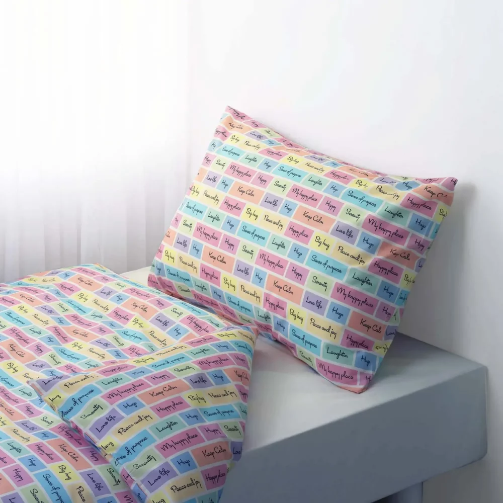 A multi-coloured pillowcase and duvet cover set from Rachel Riley. It features a series of coloured squares that include motivational slogans such as 'peace and joy' and 'keep calm'.