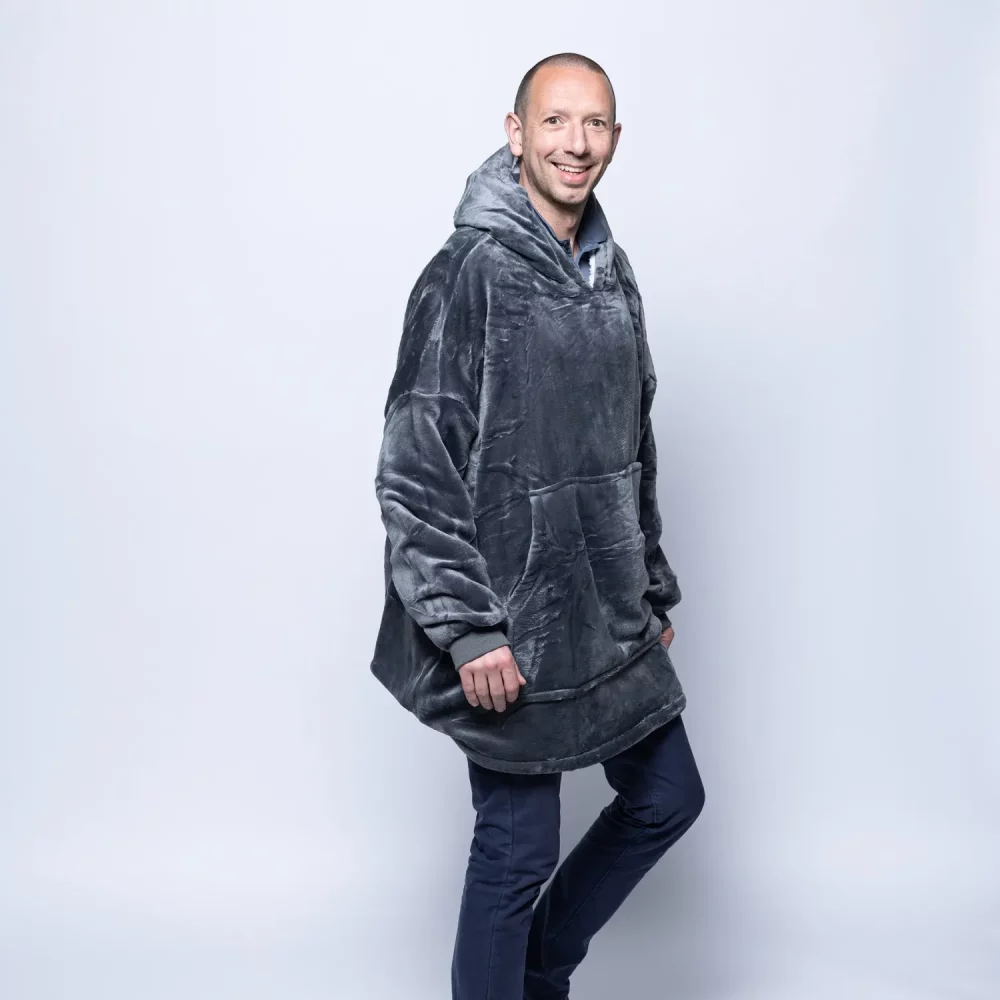 An adult male wearing a Hudi wearable blanket in charcoal.