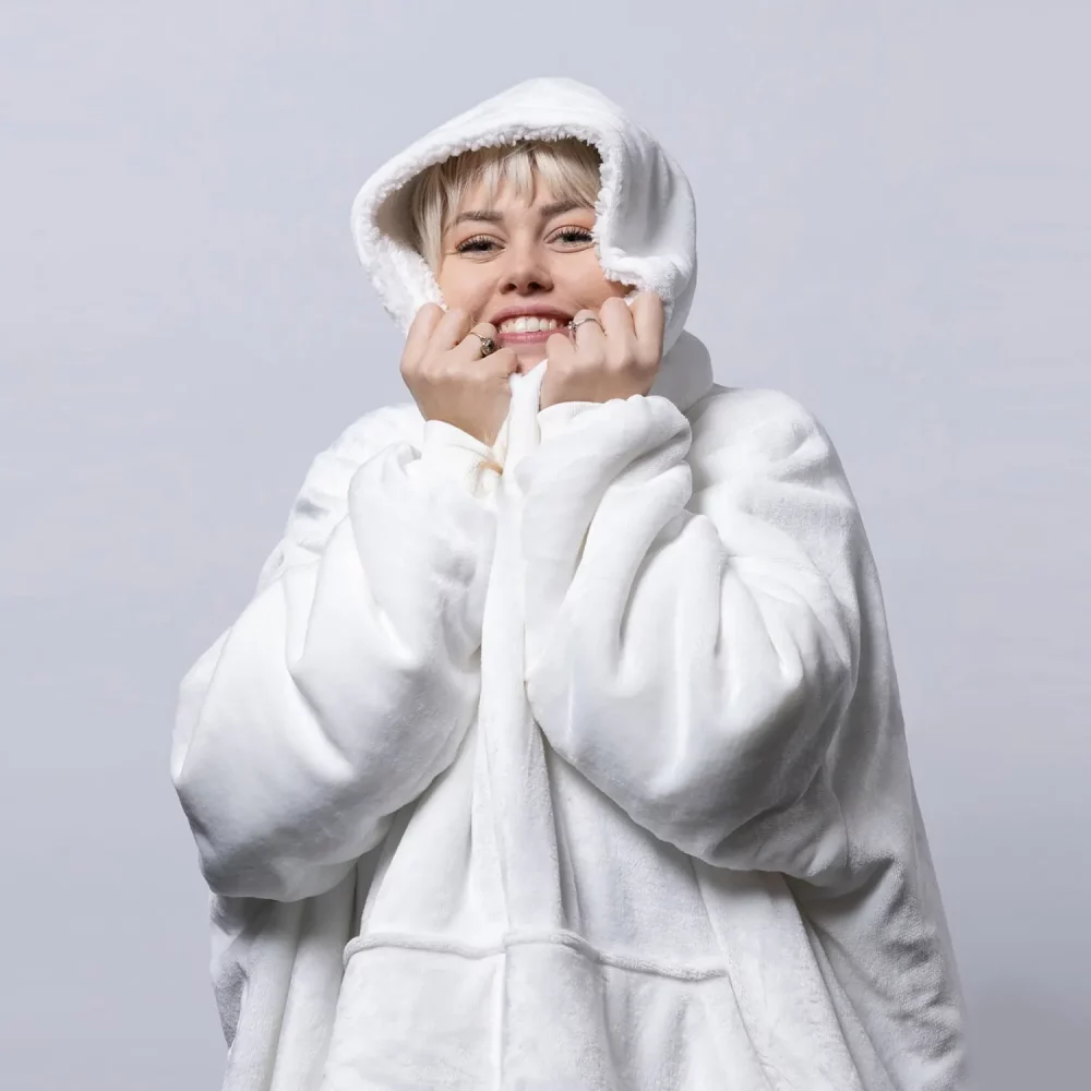 An adult female wearing a Hudi wearable blanket in cream.
