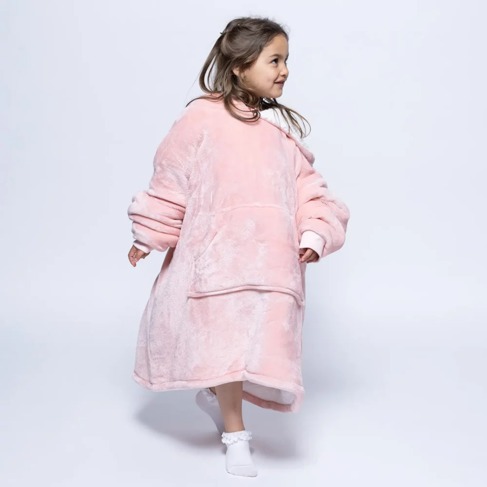 An female child wearing a Hudi wearable blanket in pink.