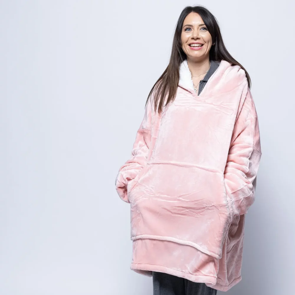 An adult woman wearing a Hudi wearable blanket in pink.