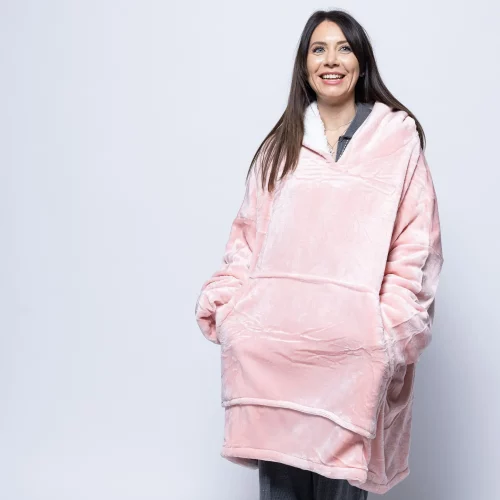 An adult woman wearing a Hudi wearable blanket in pink.