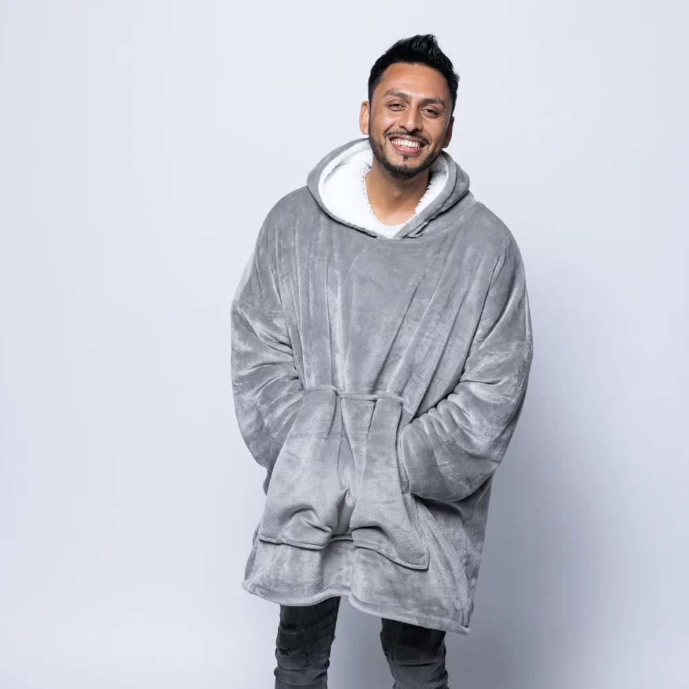 An adult male wearing a Hudi wearable blanket in silver.