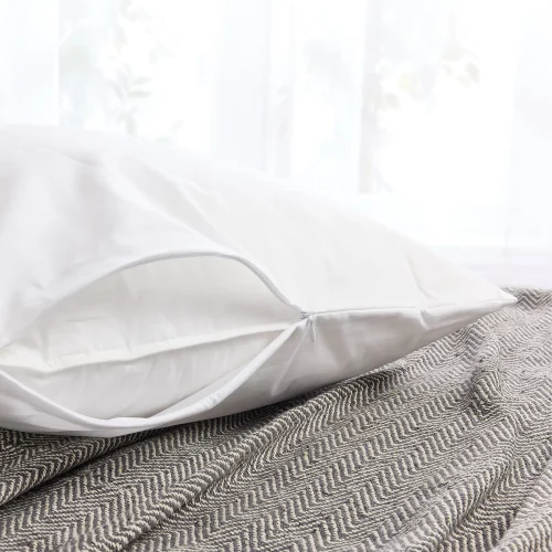 A white Hotel Pure Luxury polycotton pillow protector. You can see the zipper that's currently slightly open so you can see the pillow inside. The pillow is sitting on a grey blanket.