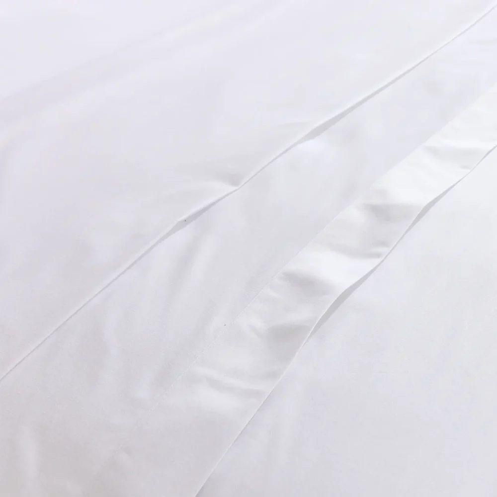 A close up of a white Hotel Pure Luxury branded cotton rich percale flat bed sheet.