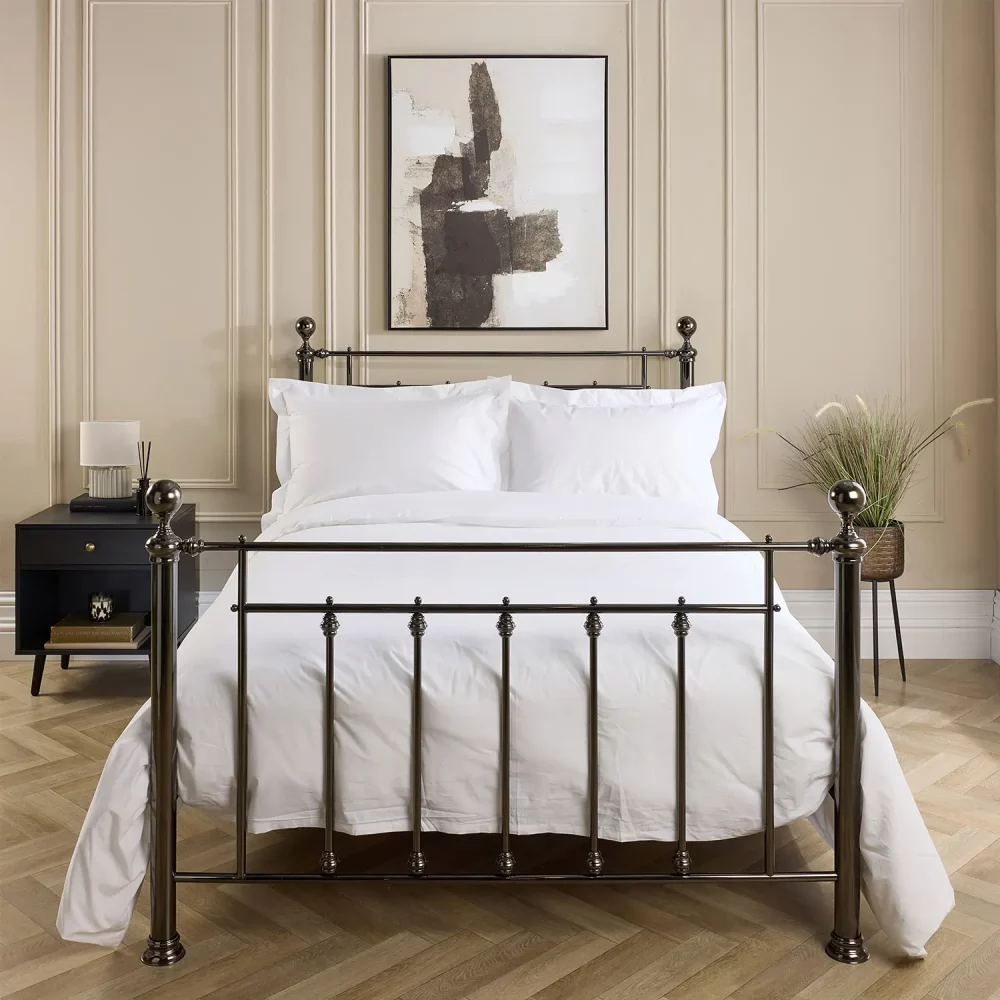 Hotel Pure Luxury cotton percale duvet cover. It's on a metal framed bed complete with white pillowcases. There is a dark wood bedside cabinet next to the bed with a lamp on top. A window is visible in the background and the bottom of a painting hanging above the bed is visible.